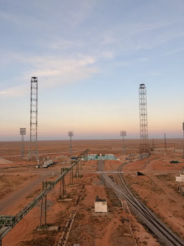 Looking down from height over rail lines, floodlight masts and the pads at sunset.