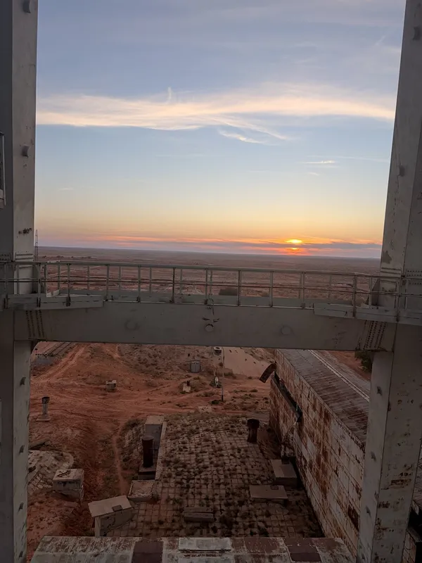 Sunset over the steppe, framed by the tower's concrete structure.