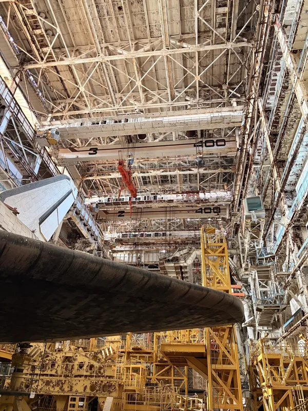The shuttle's wing tip under a vast steel roof and yellow gantries.