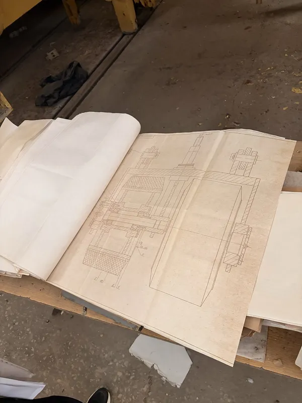 A hand-drawn technical blueprint unrolled on a table.