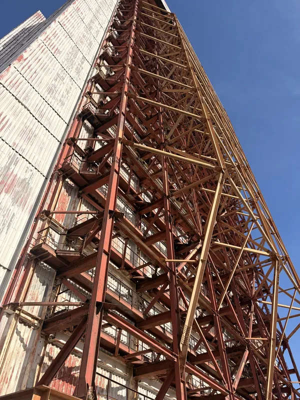 A tall red steel gantry against a blue sky.