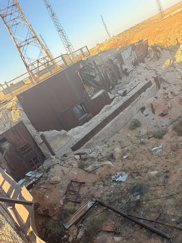 A collapsed concrete structure with twisted metal and debris.