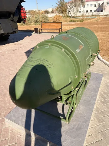 A long green cylindrical missile container on a plinth.