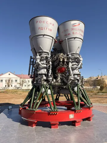 A large rocket engine with two bell nozzles on a red stand.