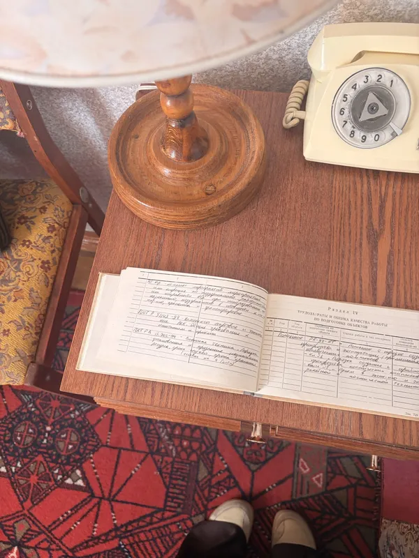 An open logbook with handwritten entries on a desk, next to a rotary telephone.